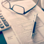 Tax forms, calculator, glasses and pen